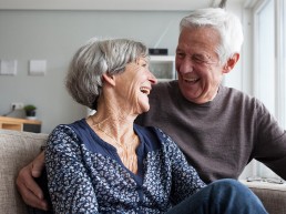 elderly couple laughing on coach together