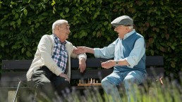 two elderly gentleman on bench chatting
