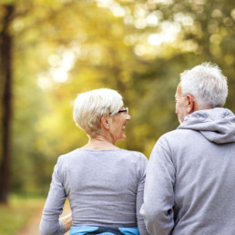 elderly couple walking close together in the park